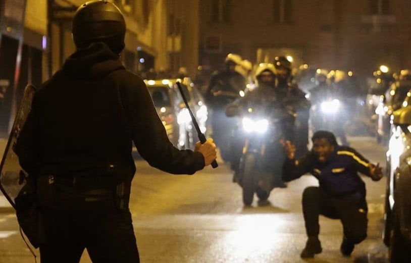 a person reacts while a police officer holds a baton during protests following the death of nahel a 17 year old teenager killed by a french police officer in nanterre during a traffic stop in paris france july 2 2023 reuters nacho doce