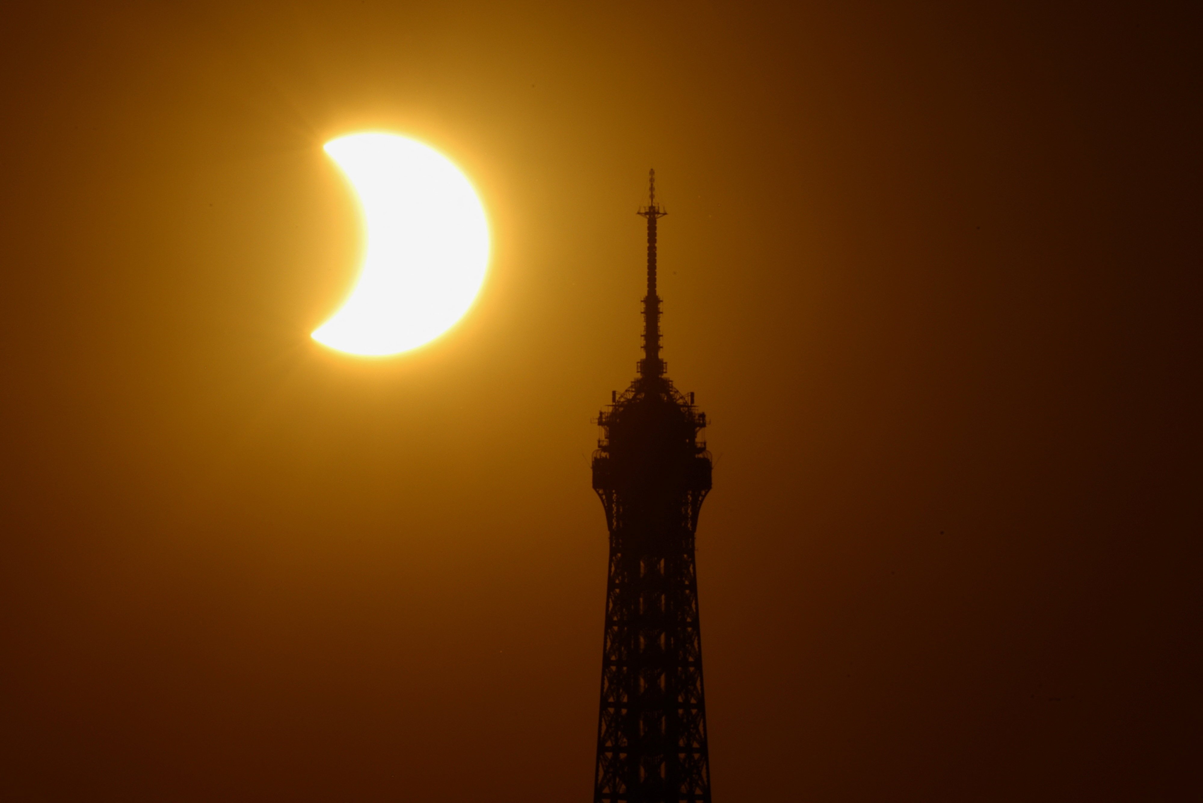 The Eiffel Tower is silhouetted as the moon partially covers the sun during a solar eclipse, as seen from Paris, France, August 12, 2026. Photo: Reuters