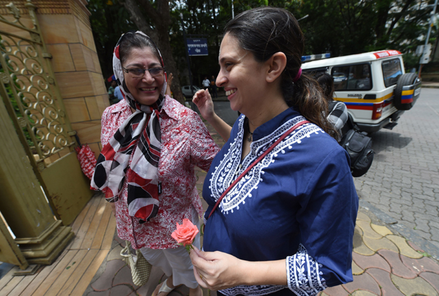This picture taken on shows Indian Parsi Pearl Tirandaz (R), six months pregnant with her second child, greeting a family friend outside a Fire Temple in Mumbai.