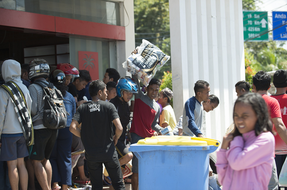 People loot a convenience store in Palu. PHOTO: AFP