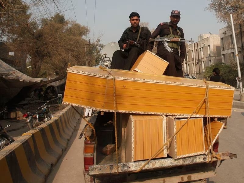 policemen stand on a pick up truck loaded with coffins for people who were killed after gunmen raided the compound of a senior government official in peshawar february 18 2013 photo reuters file