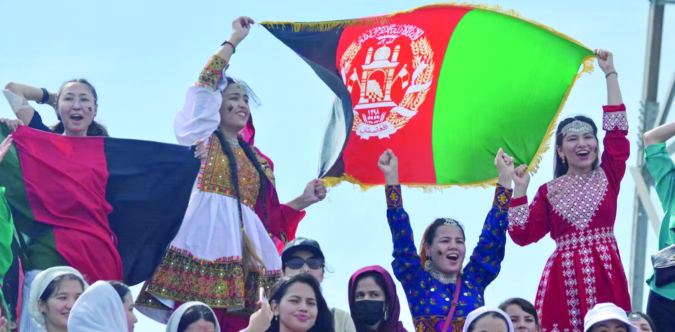 women cheer and wave the afghanistan flag during a cricket game in 2023 photo shutterstock