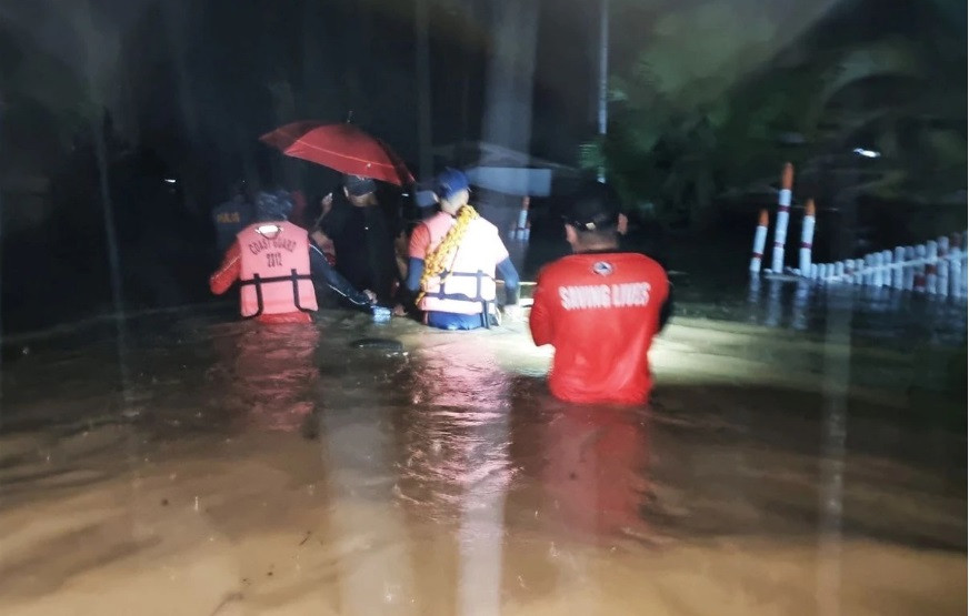 members of the philippine coast guard wade through a flooded street during a rescue operation in isabela basilan province philippines december 27 2022 philippine coast guard handout via reuters