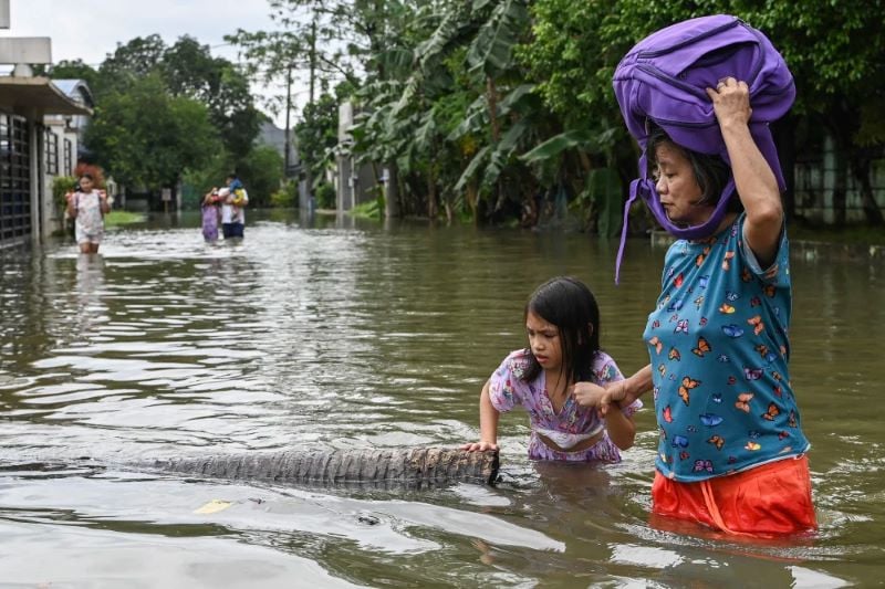 people wading through a street that was flooded by heavy rains brought about by tropical storm trami in cainta east of manila the philippines on friday photo afp