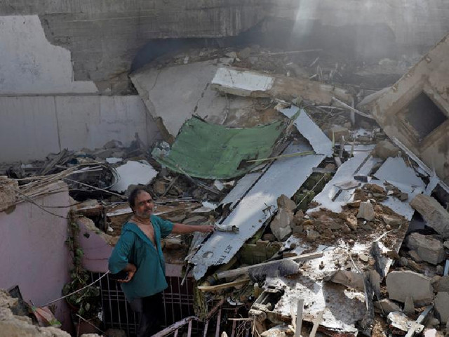 a man stands on the debris of a house at the site of a passenger plane crash in a residential area near an airport in karachi photo reuters file