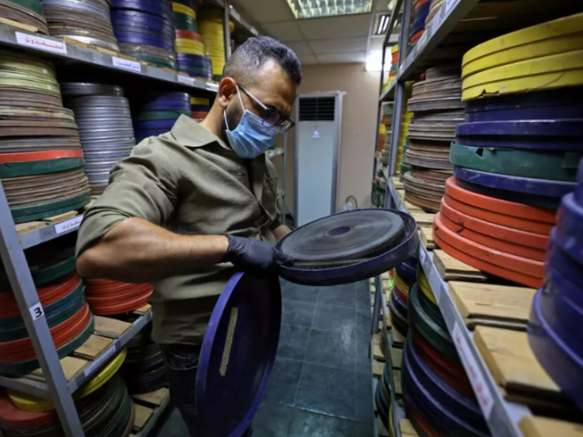 Photo: Producer Haider Ibrahim inspects a film reel at the National Centre for Archives and Iraqi Memory in Baghdad/AFP