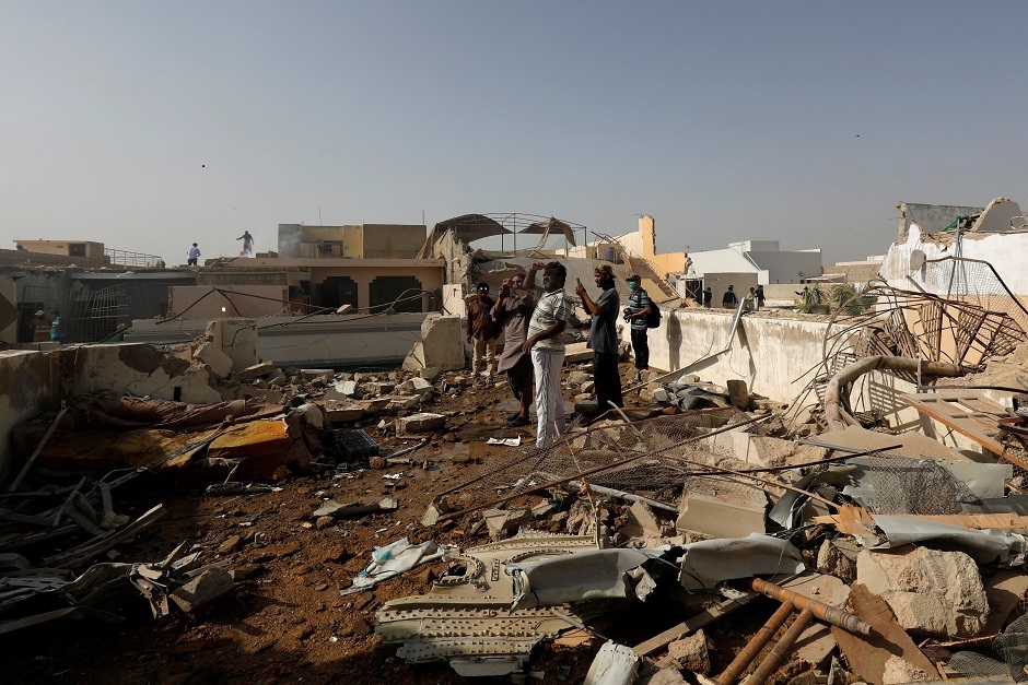 People stand on a roof of a house amidst debris of a passenger plane, crashed in a residential area near an airport in Karachi, May 22. PHOTO: REUTERS