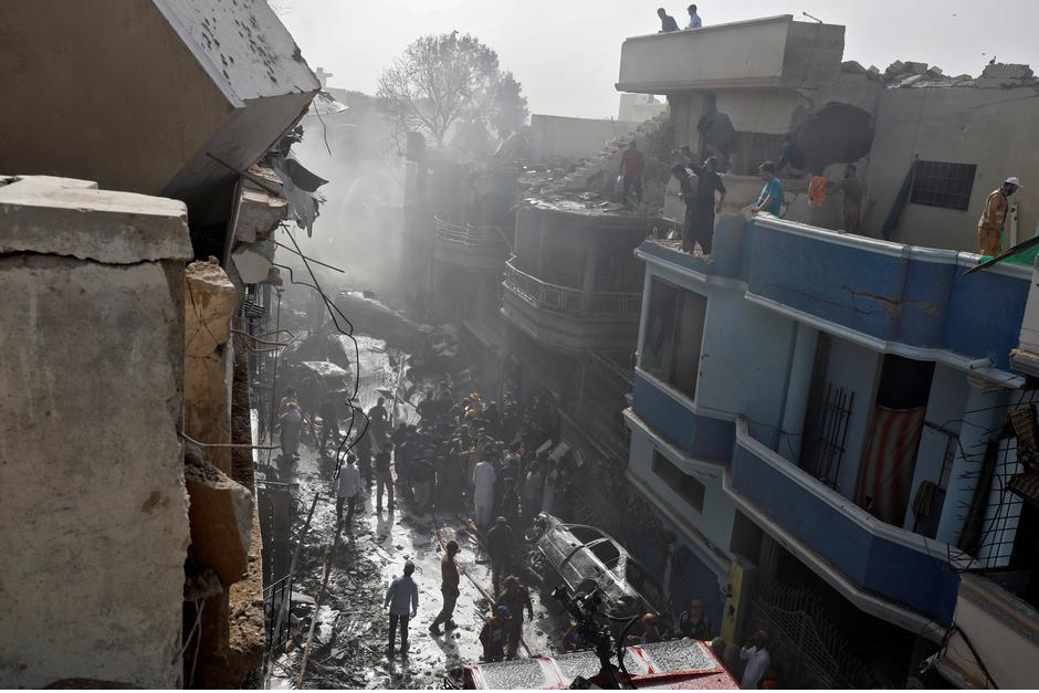 Rescue workers carry a victim at the site of a passenger plane crash in a residential area near an airport in Karachi. PHOTO: REUTERS