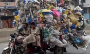 men drive a three wheeler loaded with used plastic bags in lahore photo afp