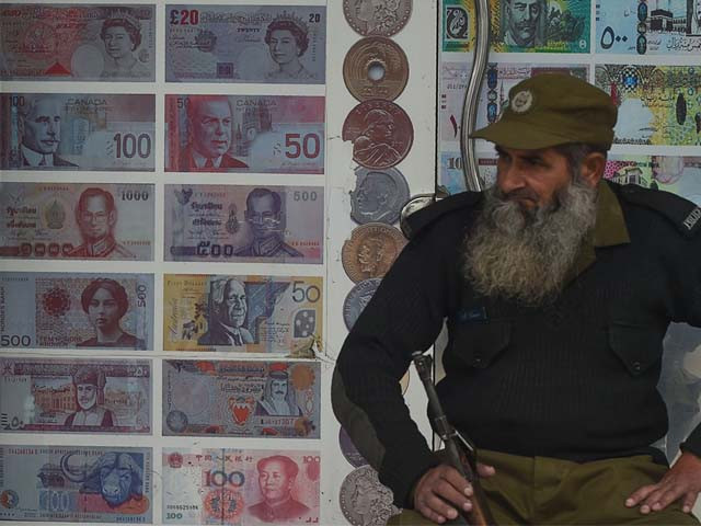 a security guard sits outside a currency exchange shop in lahore photo afp