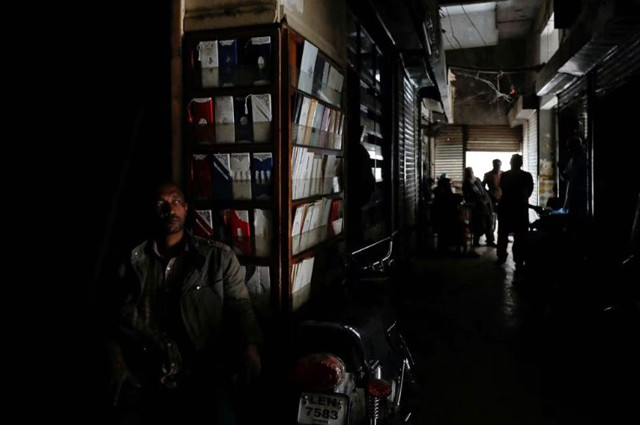 a man sits outside his shop during a country wide power breakdown in karachi pakistan january 23 2023 photo reuters