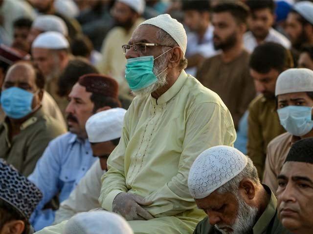 a muslim devotee wearing a facemask offers prayers during the eid ul azha photo afp