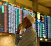 a stock broker reacts while monitoring the market on the electronic board displaying share prices during trading session at the pakistan stock exchange in karachi on july 3 2023 photo reuters file