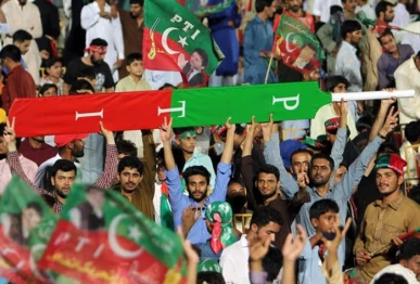 supporters of former prime minister imran khan hold a giant cricket bat with the colours and initials of the party photo afp file