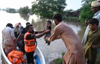 rescuers in a small boat hand over a baby as they evacuate residents from the flooded area of narowal a city of punjab on august 27 2025 photo afp