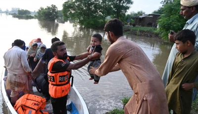 rescuers in a small boat hand over a baby as they evacuate residents from the flooded area of narowal a city of punjab on august 27 2025 photo afp