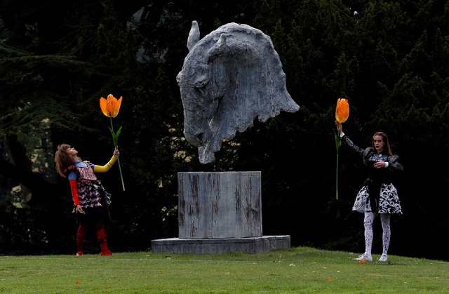 Dancers perform next to a sculpture entitled