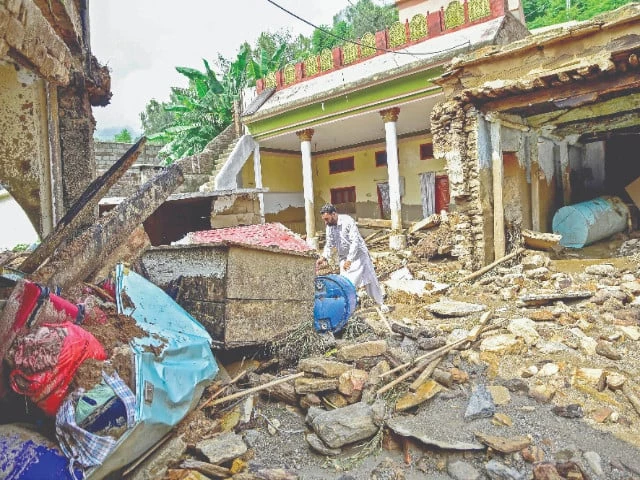 a resident of buner sifts through the mud caked remnants of his home after devastating rains and flash floods photo afp