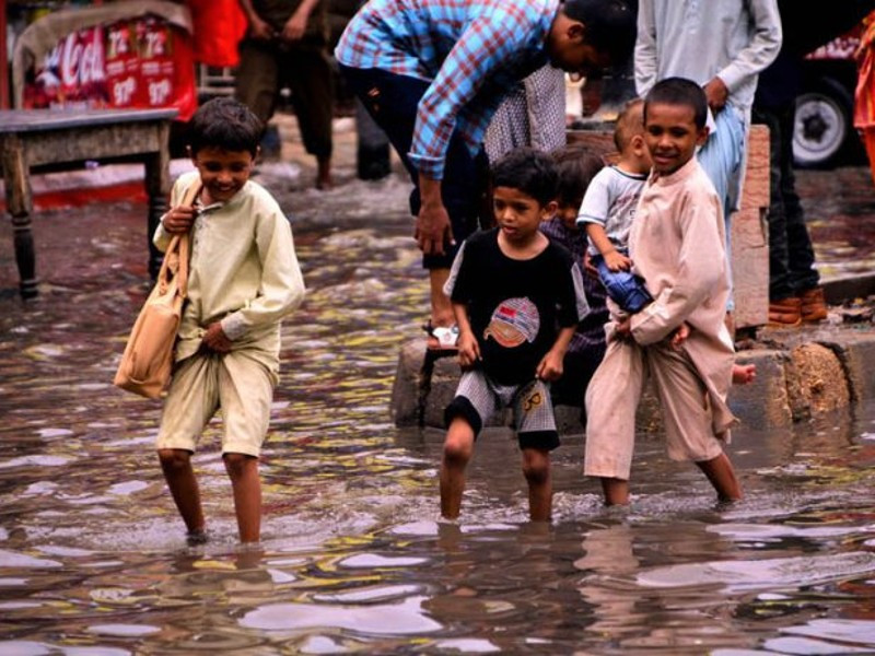children crossing through rain water accumulated at railway station road in hyderabad after heavy rain in the city photo app