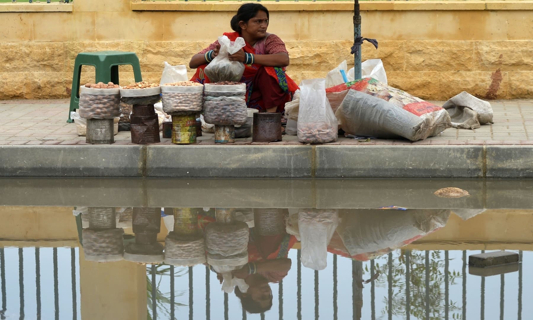 a dry fruit vendor waits for customers alongside a street inundated with rainwater in karachi photo afp