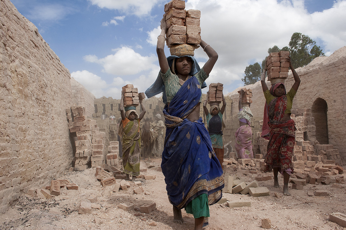 A couple of female kiln workers walk through in extreme summer.