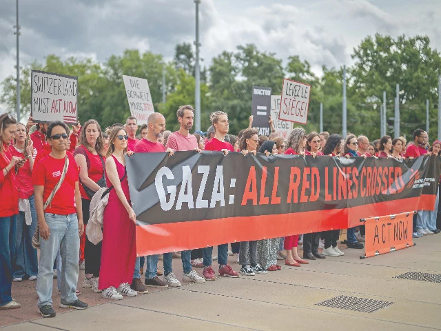 staffs of doctors without borders medecins sans frontieres msf march behind a banner carrying placards as they stage a demonstration against the militarisation of supplies of humanitarian aid in the gaza strip next to the united nations offices in geneva photo afp