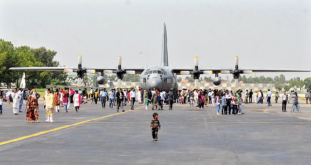 a number of people keenly watching aircraft and weapons displayed at nur khan air base photo app