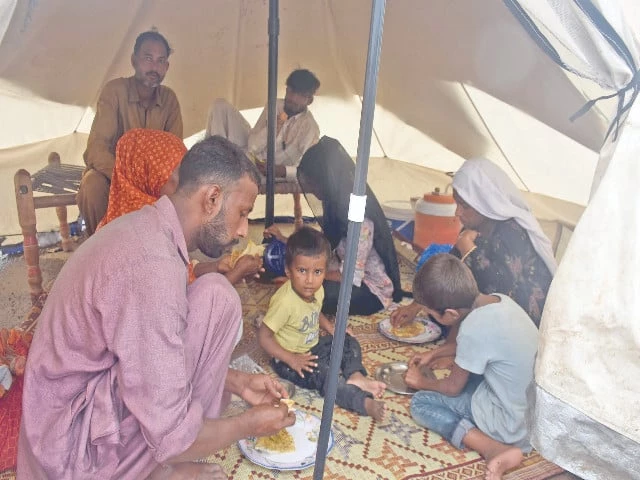 a flood affected family has a meal in a makeshift camp in lahore the pakistan meteorological department has forecast more showers in the city over the next 24 hours photo online