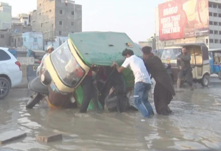 a rickshaw falls into a sewage filled crater on university road prompting bystanders to rush in and pull it to safety photo express