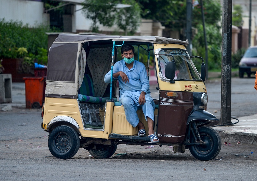 a man sits in his rickshaw with a loosely worn mask photo afp