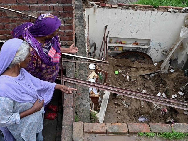 neighbours look at collapsed roof of house during heavy monsoon rains in lahore on july 16 2025 photo afp neighbours look at collapsed roof of house during heavy monsoon rains in lahore on july 16 2025 photo afp