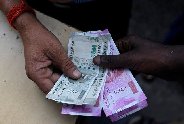 a customer hands indian currency notes to an attendant at a fuel station in mumbai india august 13 2018 photo reuters a customer hands indian currency notes to an attendant at a fuel station in mumbai india august 13 2018 photo reuters
