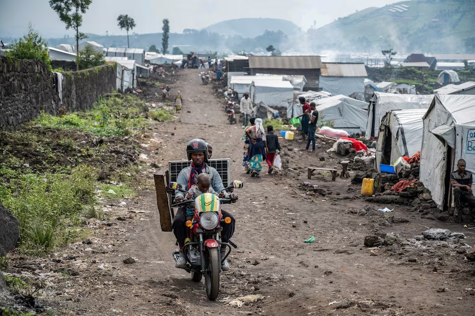 people ride past congolese people displaced by recent clashes between the m23 rebels and the armed forces of the democratic republic of the congo fardc as they prepare to leave the camp after being instructed by the m23 rebels to vacate the camps on the outskirts of goma democratic republic of the congo on february 12 2025 photo reuters