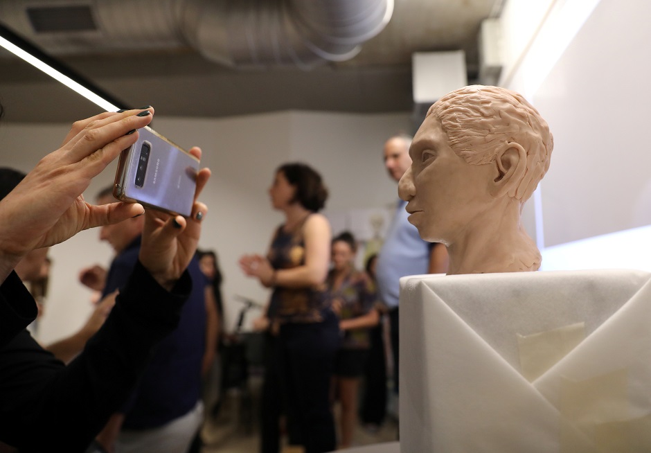  A woman takes a photograph of the artistic rendering of the head and face of a 13-year-old girl from the the prehistoric human species. PHOTO: REUTERS 