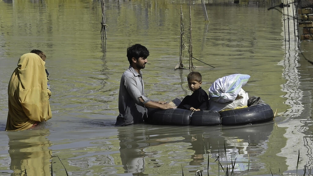 a family wades through a flood hit area following heavy monsoon rains in charsadda district of khyber pakhtunkhwa afp