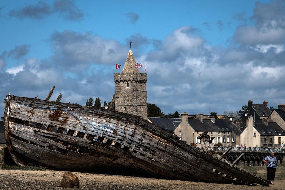 This picture taken shows a woman near a ship wreck at Port-bail northwestern France. PHOTO: AFP