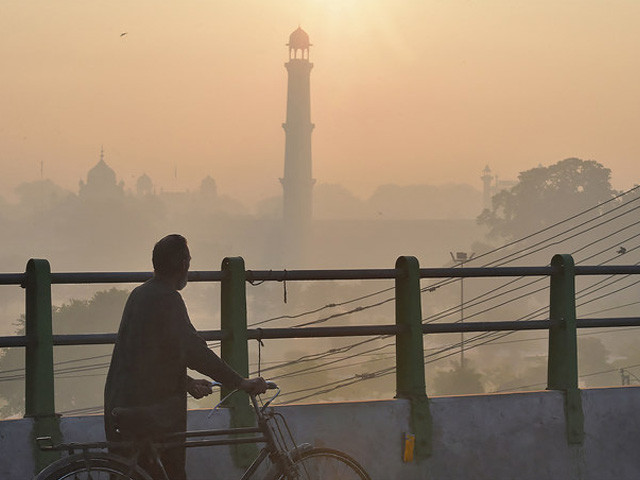 a man walks with a bicycle along a bridge amid heavy smog conditions near badshahi mosque in lahore pakistan on december 6 2019 photo afp