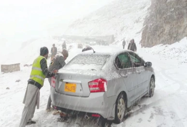 workers push a stranded car along a snow covered road in abbottabad after the region received its first snowfall of the season photo ppi