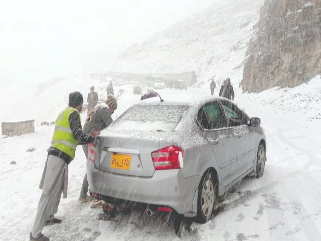workers push a stranded car along a snow covered road in abbottabad after the region received its first snowfall of the season photo ppi