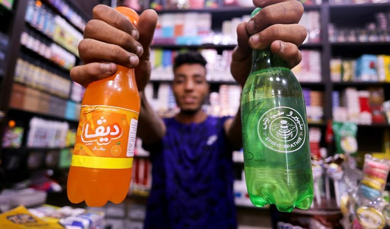 an egyptian supermarket owner shows bottles of egypt s local beverage brands spiro spathis and diva masr at his store in cairo egypt on september 1 2024 photo reuters