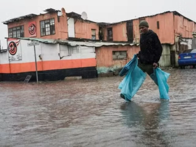a resident walks across a flooded road following severe weather with heavy rain from a cold front in masiphumelele cape town south africa on may 20 2025 photo reuters file