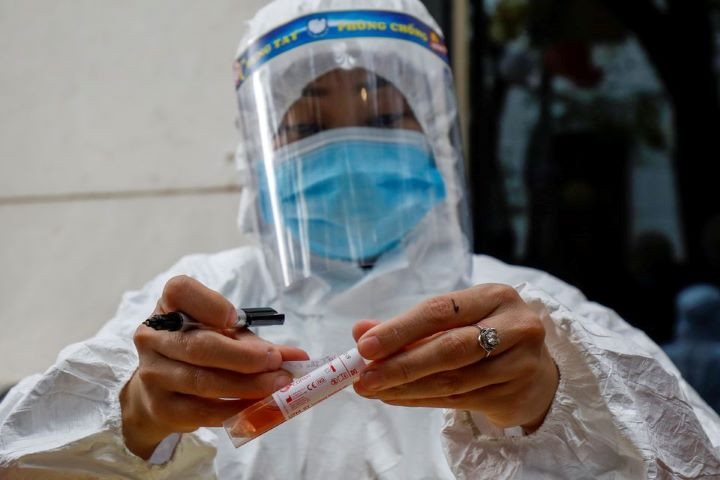 a health worker wearing a protective suit labels a sample tube at the national convention center the venue for the 13th national congress of the communist party of vietnam during the coronavirus disease covid 19 outbreak in hanoi vietnam january 29 2021 reuters kham