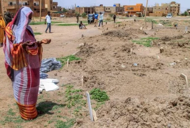 a woman prays by one of the makeshift graves of those buried in khartoum s southern suburb of al azhari on august 2 2025 when the area was under control of the rapid support forces rsf paramilitaries which will be exhumed for reburial in the local cemetery photo afp