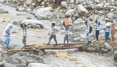 volunteers carry food medicine and other supplies for flood victims as they cross a rocky river in buner district khyber pakhtunkhwa photo afp