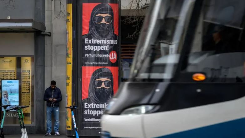 a tram passes by campaign posters in favor of the burqa ban initiative reading in german stop extremism on march 3 2021 in the streets of zurich photo afp file