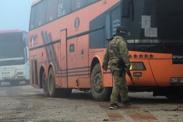 A rebel fighter stands near buses carrying people evacuated from the two villages of Kefraya and al-Foua, after an agreement reached between rebels and Syria's army, at insurgent-held al-Rashideen, Aleppo province, Syria April 14, 2017. PHOTO: REUTERS