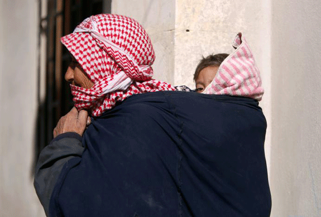  A woman carries a child as she walks in Aleppo's Jibreen shelter, Syria February 1, 2017. PHOTO: REUTERS