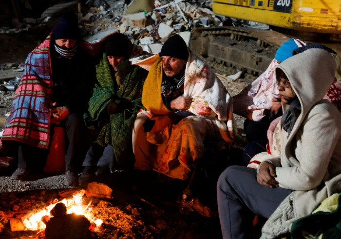 Zubeyde Kahraman (R), whose sister Zeynep, 40, is being rescued by ISAR Germany, waits by a fire with her family during the rescue operation that ISAR Germany say has taken almost 50 hours, as the search for survivors continues, in the aftermath of a deadly earthquake in Kirikhan, Turkey February 10, 2023. REUTERS/Piroschka van de Wouw