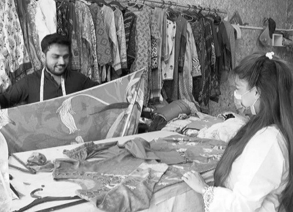 a tailor and his client discus the cut of the dress she has ordered photo express