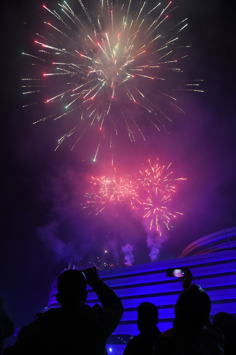 People take pictures with their smartphones as fireworks explode during the New Year celebrations in Rawalpindi.